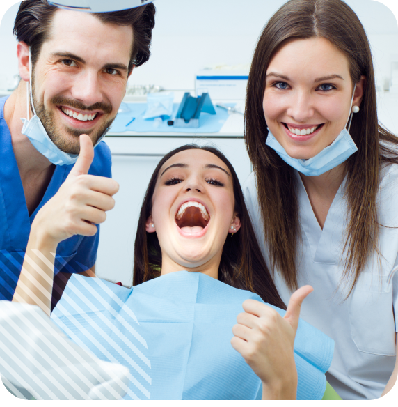 Two dental professionals and a female patient giving thumbs-up in a cheerful dental clinic environment